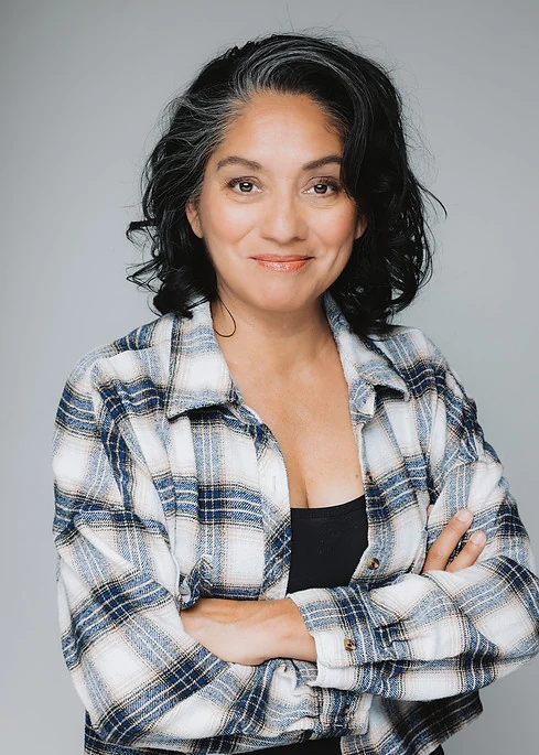 Teresa Cisneros wearing a plaid shirt with her arms crossed.